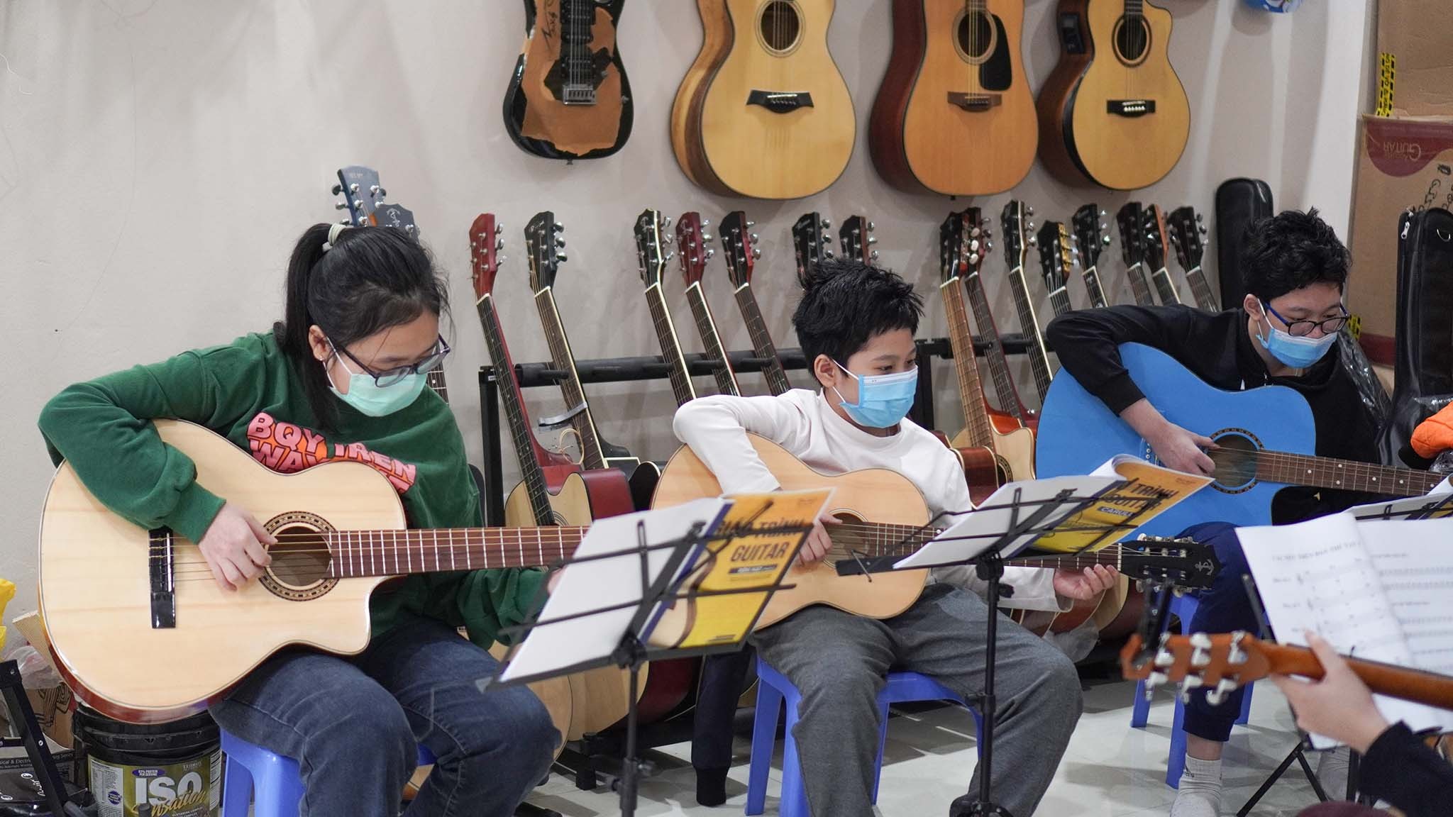 Học viên đang chăm chú thực hành trên đàn guitar, tập trung vào kỹ thuật ngón