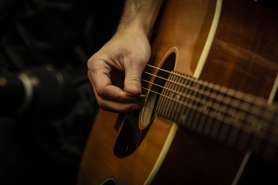 Một nghệ sĩ guitar đang biểu diễn trên sân khấu, tập trung vào kỹ thuật đệm và giữ nhịp cho ban nhạc